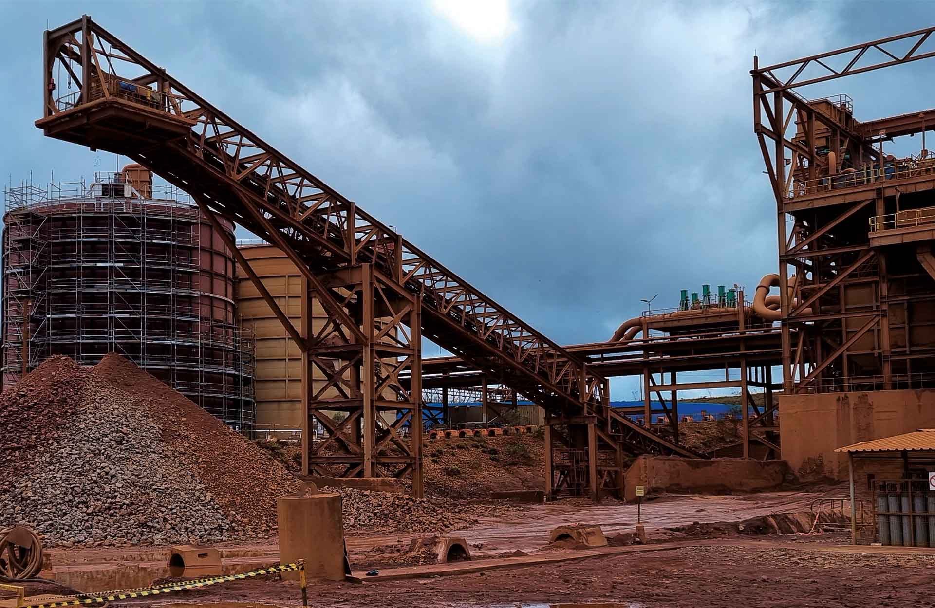 Processing plant under construction: tanks in scaffolding, conveyor gallery and stockpile