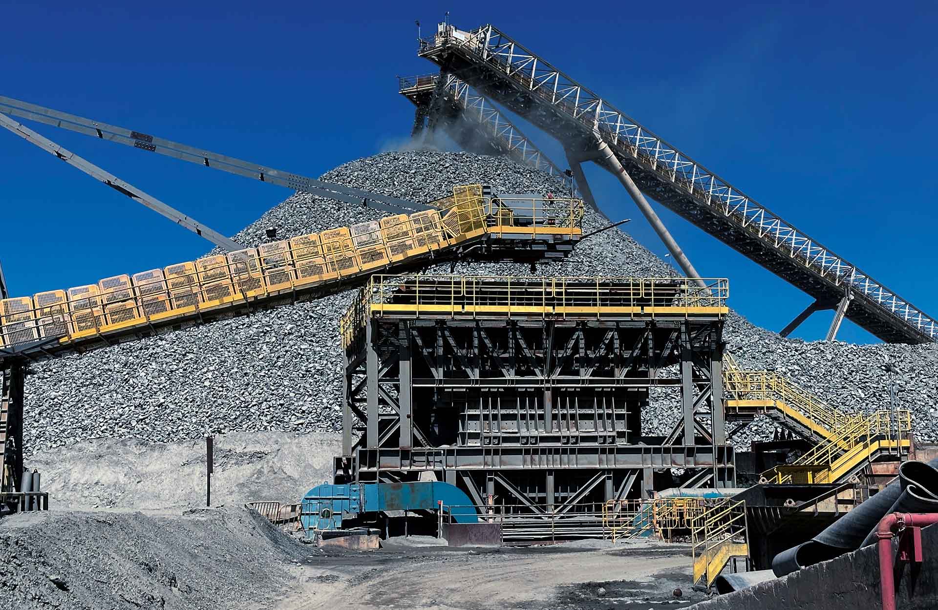 Crushing plant with stacker and stockpile under a clear sky